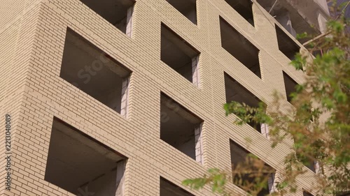 Unfinished brick facade of multistory residential building under construction