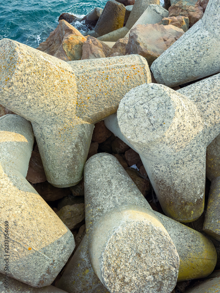 Fototapeta premium Concrete barriers on a rocky shore near the sea during daylight showing water and sky