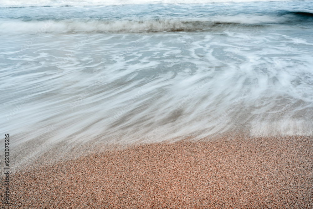 Fototapeta premium long exposure of waves crashing on sandy beach