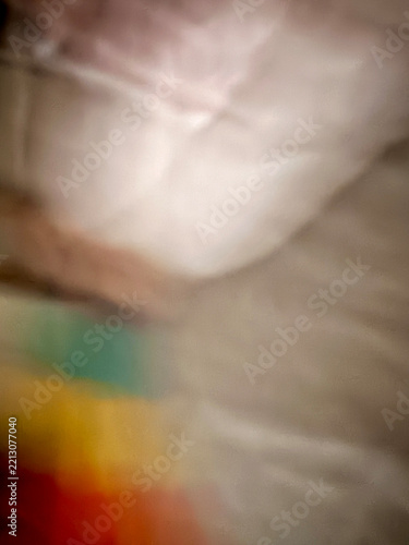 A highly blurred scene showing various soft color fields. Red, orange, yellow, and green tones blend with light beige and hints of pink.