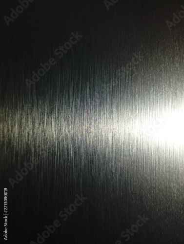 Bright light reflecting on silver brushed metal texture background.