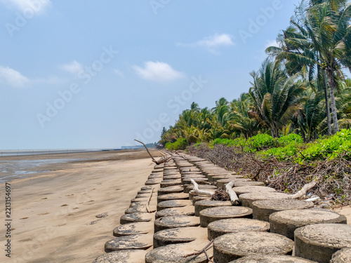 Concrete seawall blocks on tropical beach under bright sunlight