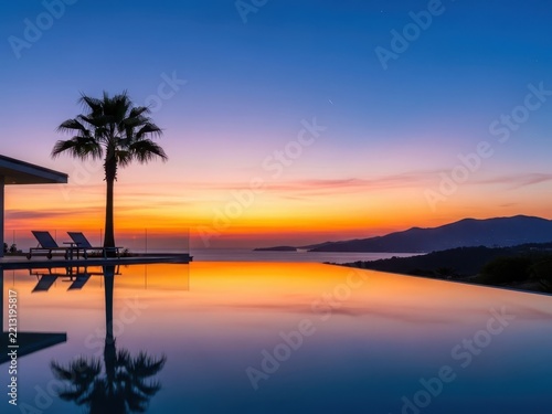 Palm tree silhouette at sunset over calm water