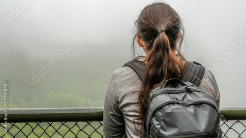 Woman with backpack looking out at fog.