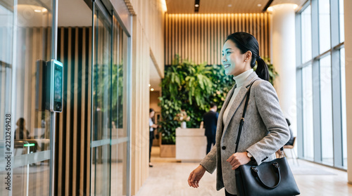 Woman walking through office automatic glass entrance with scanner