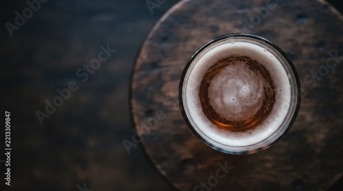 Golden brew rests in a glass atop a rustic wooden table, capturing the warmth of a cozy setting in the late afternoon Generative AI