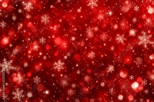 Festive red background with blurred bokeh lights and delicate falling snowflakes