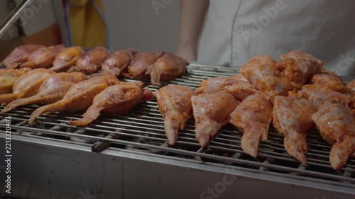 Seasoned raw poultry pieces arranged on metal grill racks for grilling preparation in a food service setting.
