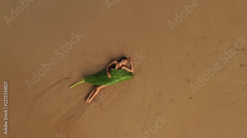 Woman Lying on a Banana Leaf on Sandy Beach Top View
