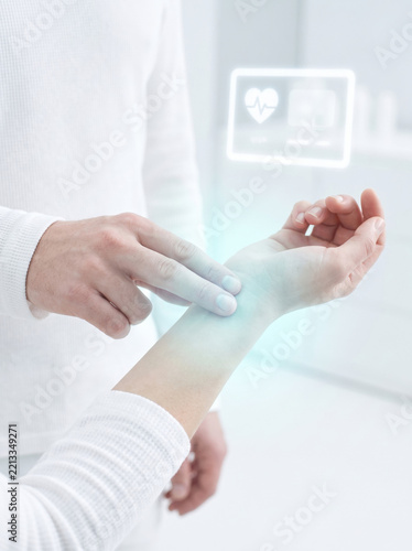 Pulse check on wrist with digital health screen, expressing modern medical care and wellness monitoring
