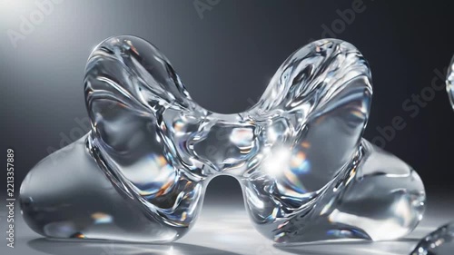 Abstract liquid glass shapes moving and reflecting light on a smooth dark grey studio surface