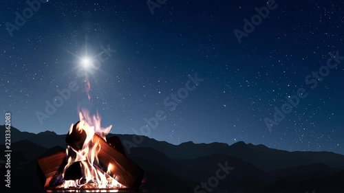 A campfire flickers beneath a brilliant star and a starry sky above dark mountains, evoking Christmas Eve.