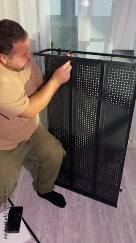 A man screws a screw into a metal shelving unit