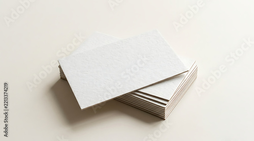 A stack of blank white business cards with visible paper edges resting on a light beige surface with soft shadows and clean composition isolated on a transparent background