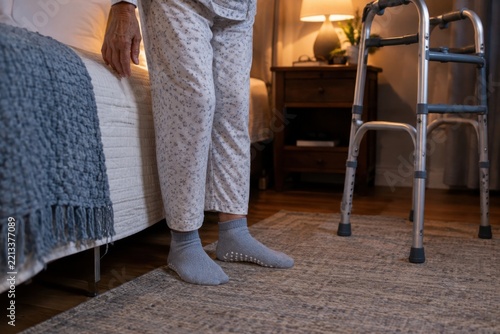 Close-up of secure nonslip socks on an older adult standing beside a bed, walker nearby, senior care and healthy aging concept