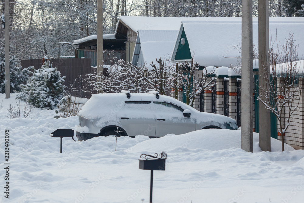 Obraz premium Snow covers a parked car and surrounding yard