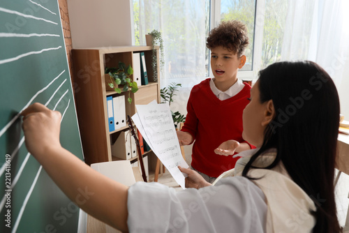 Music education and private tutoring, teacher drawing staff lines on chalkboa...