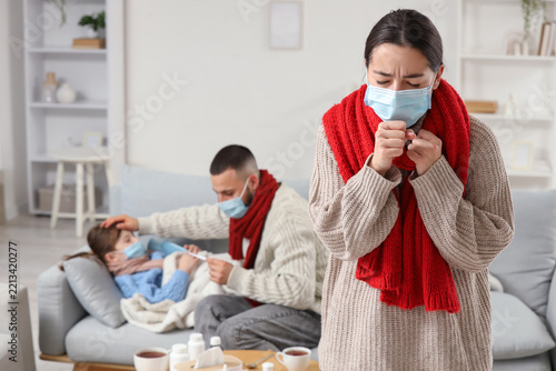 Ill young woman in medical mask with her family at home