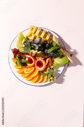 Sliced tropical fruit platter with mint leaves on ceramic plate food