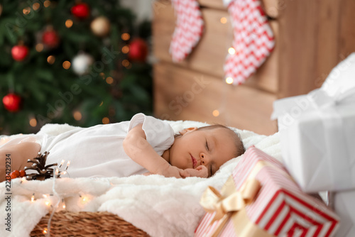 Cute little baby sleeping in wicker basket on Christmas eve