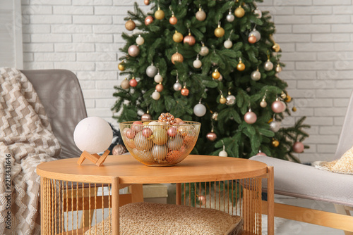 Bowl with Christmas baubles and lamp on coffee table in living room, closeup