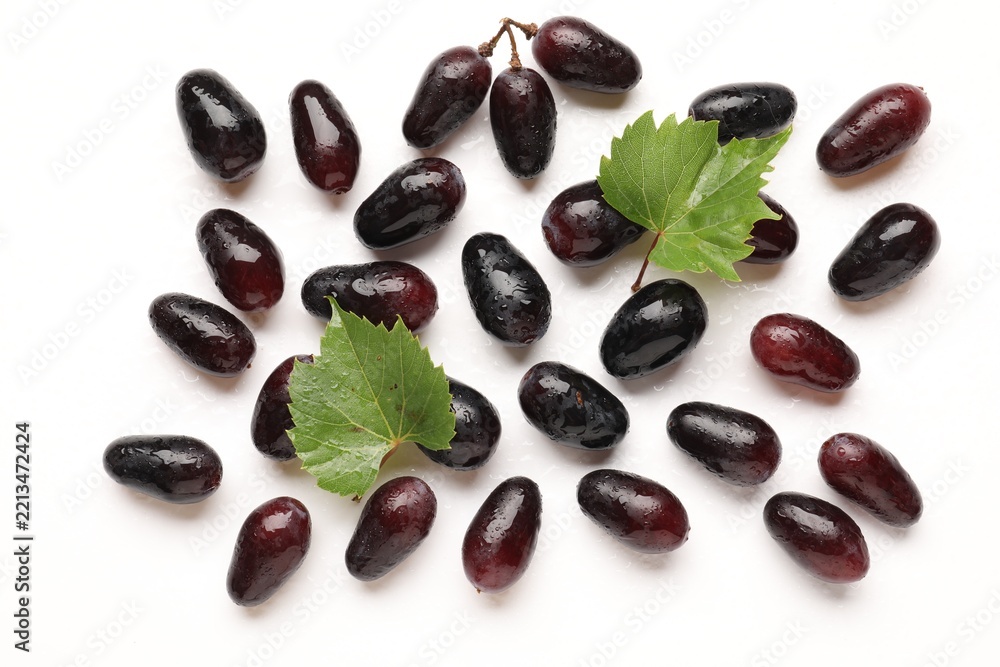Naklejka premium Fresh ripe grapes and green leaves on white background, flat lay