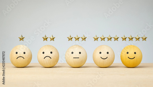 Wooden sphere wooden balls showing customer review ranking system with different facial expressions and shiny gold stars arranged horizontally on surface