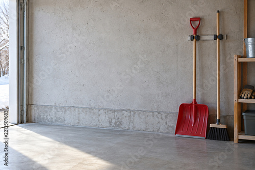 Snow shovel and broom stored in a garage for winter preparedness