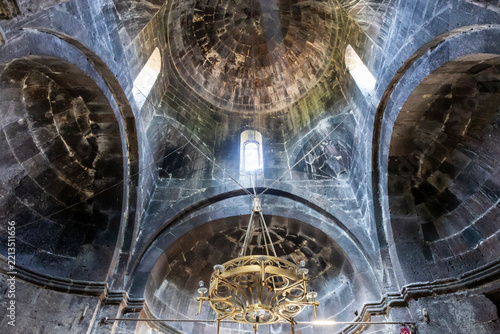 Stone dome and arched ceiling with a hanging chandelier rise above the vaulted interior of the ancient monastery church in Gegharkunik Province, Artsvanist, Armenia