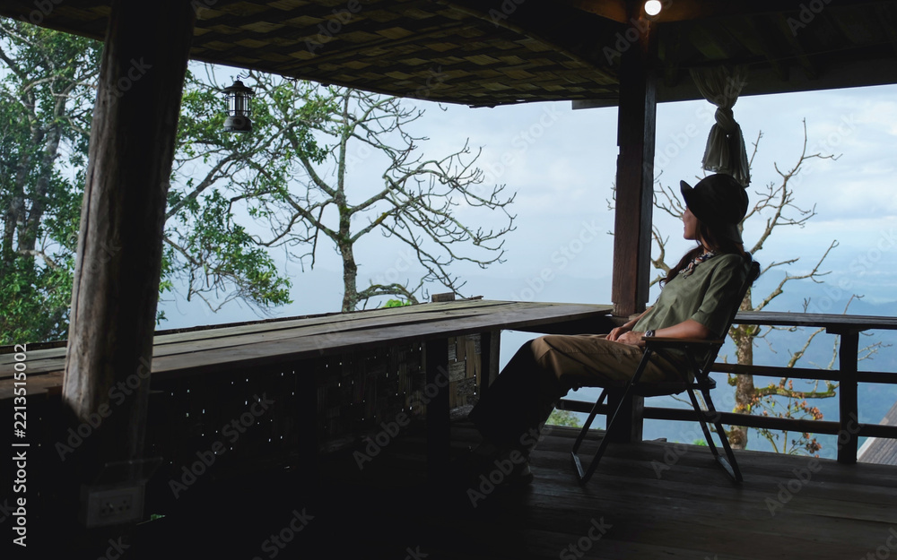 Fototapeta premium A woman sitting on wooden terrace and looking at nature views
