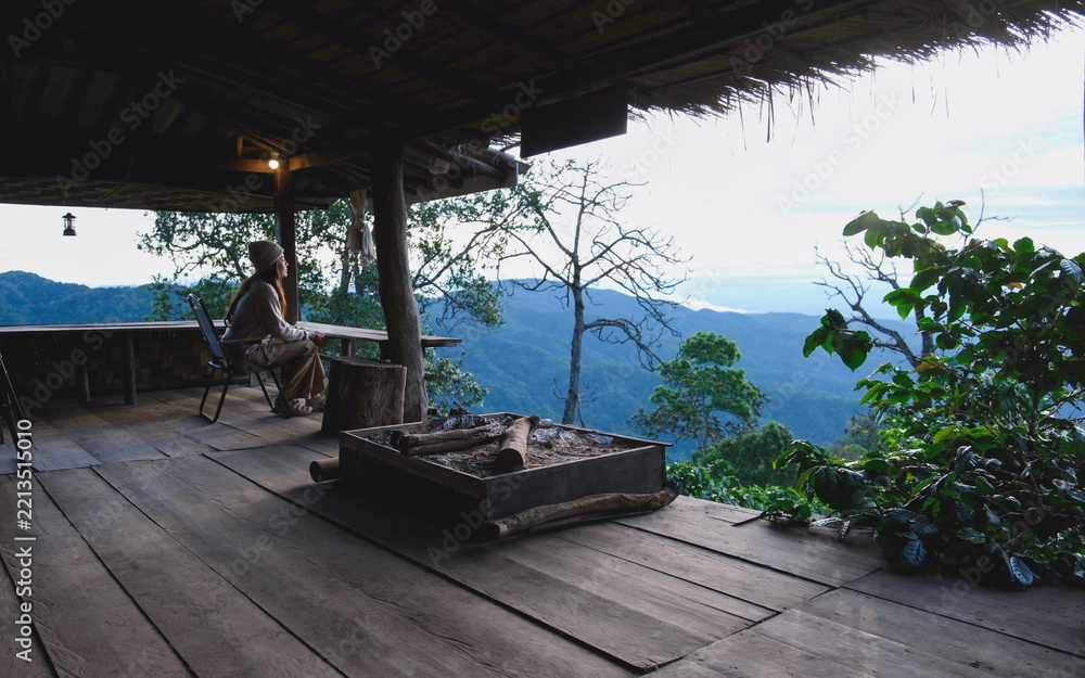 Fototapeta premium A woman sitting on wooden terrace and looking at nature views