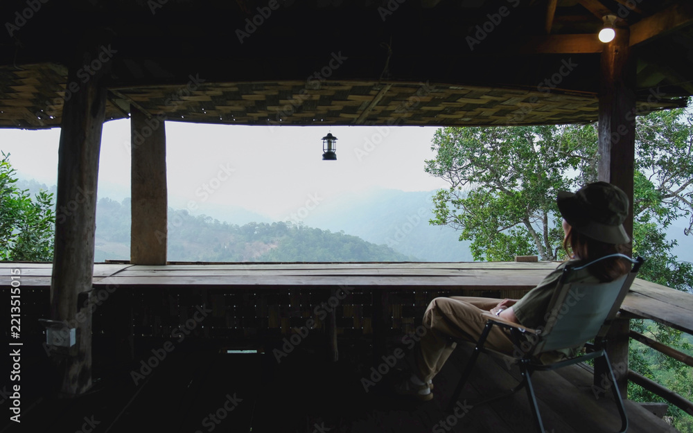 Fototapeta premium A woman sitting on wooden terrace and looking at nature views