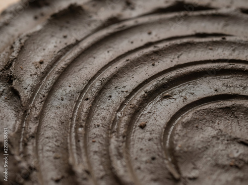 Macro close-up of wet dark clay with circular pottery wheel grooves