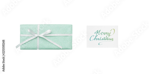 A pale pale green gift box and a white Christmas card with yellow-green handwritten text, seen from above
