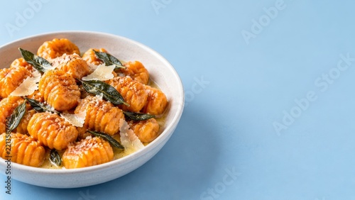 Golden Gnocchi with Sage Butter and Shaved Cheese on a Pale Blue Table