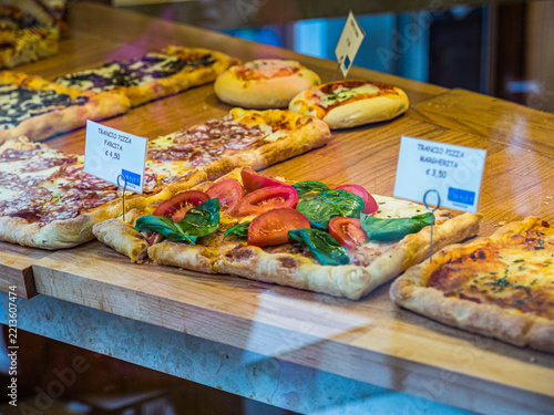 Obraz na plátně VENICE, ITALY - APRIL 6, 2016: Assorted pizza slices with tomato, basil, cheese and salami displayed for sale at Majer Venezia bakery