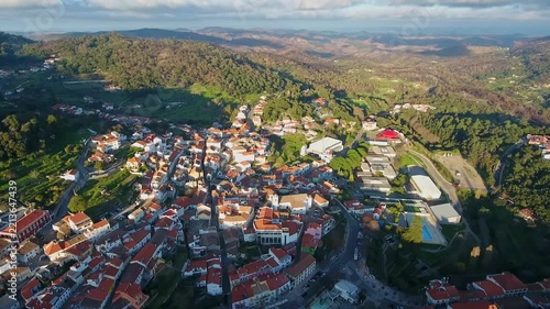 Drone footage capturing the picturesque town of monchique, nestled in the green mountains of the algarve region in portugal, featuring traditional houses with red tile roofs at sunset