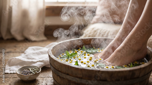 Warm herbal foot bath with steam and flowers in cozy interior  