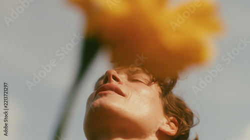 Woman enjoying sunlight with yellow flower
