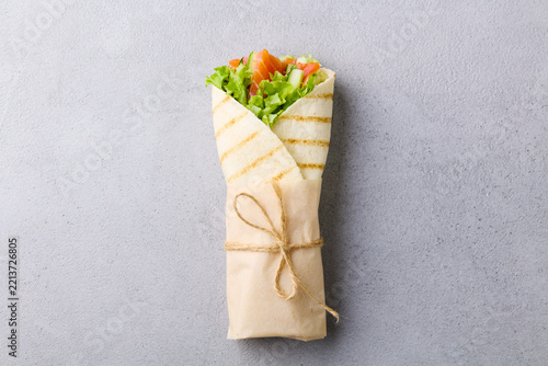 Wrap sandwich, roll with fish salmon and vegetables. Grey background. Close up, copy space. Top view.