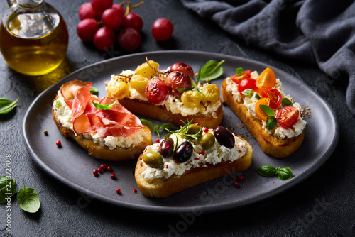 Delicious Mediterranean bruschetta assortment on dark plate. Dark grey background. Close up.