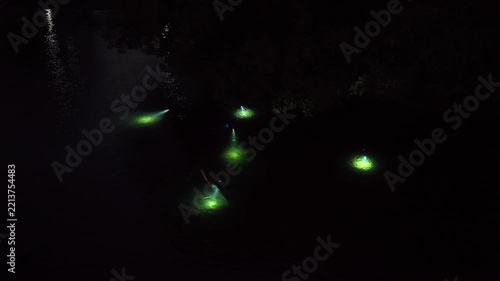 An aerial view shows snorkelers exploring a shallow underwater habitat at night in Lembeh Strait, Indonesia. This area of North Sulawesi is famous for its rare, black sand-associated marine life.
