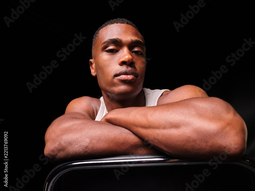 Determined muscular man resting arms on chair back