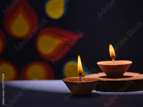 Two clay diyas with flickering flames illuminate a dark