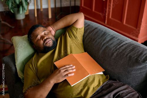 Man Resting on a Couch With a Book