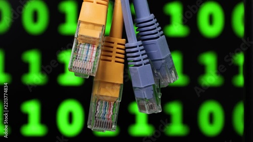 Close-up of multiple ethernet cables featuring different colors against a background of glowing green binary code.
