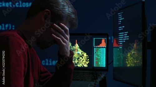 Overworked coder dealing with stress, fatigue and anxiety while completing programming tasks under pressure in dark workspace at night. Programmer experiencing burnout. 