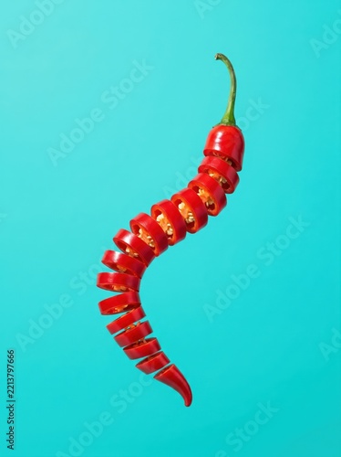 Levitating sliced red chili pepper on turquoise background