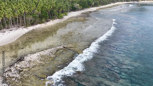 Calm seas bathe the beautiful coastline of the remote Maju Island in the Molucca Sea, Indonesia. A rugged, rocky reef surrounds this tropical paradise which few people ever visit.
