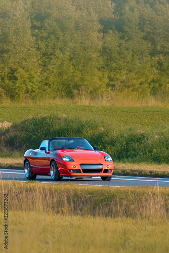Open roof convertible car cruising rural landscape